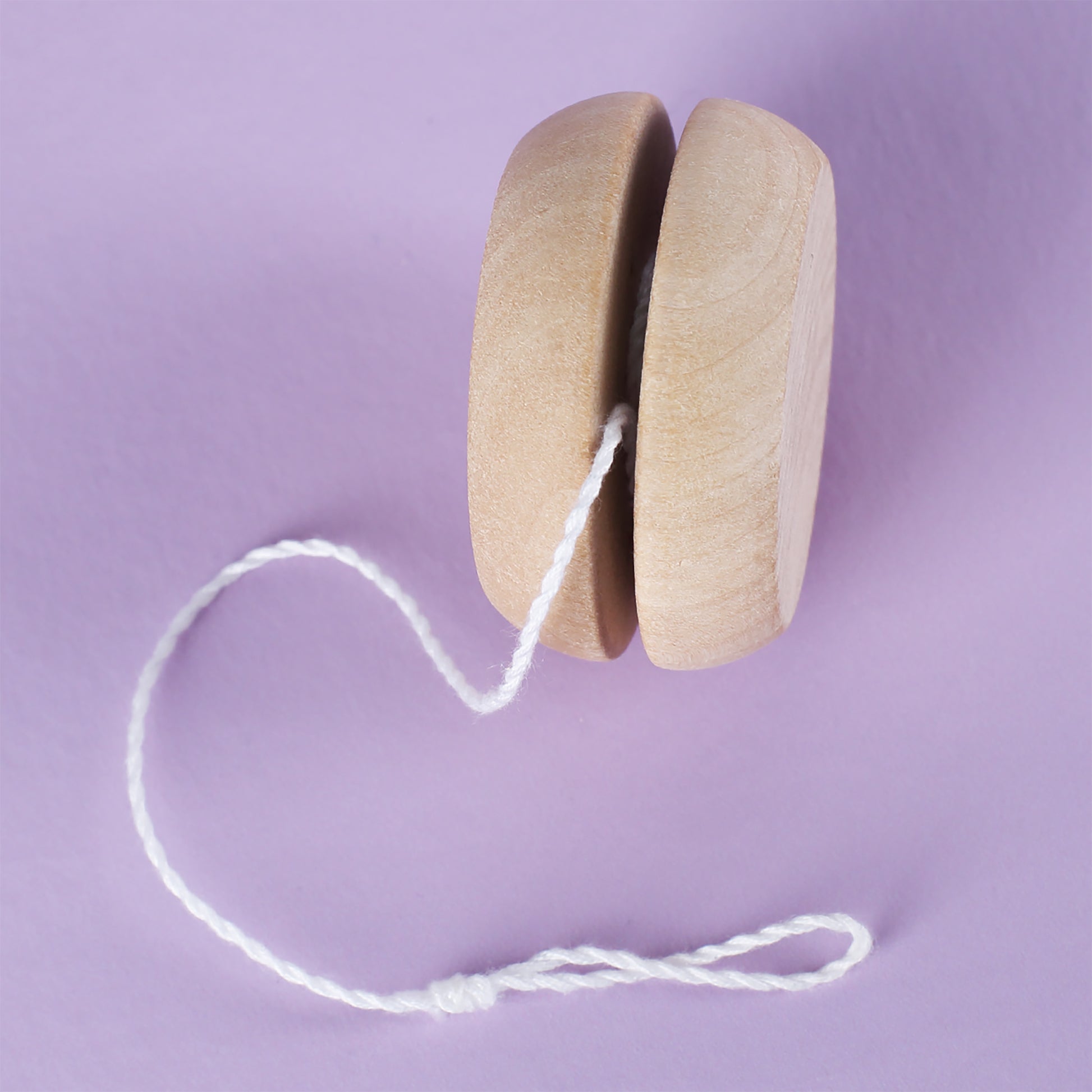Seitenansicht des Holz-Yo-Yos mit Schnur auf lila Hintergrund