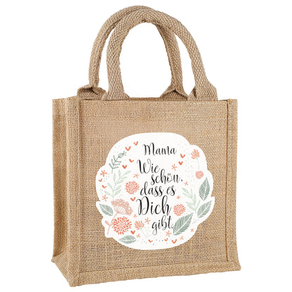 Geschenktasche mit Blumendruck und Text, freigestellt auf weißem Hintergrund.