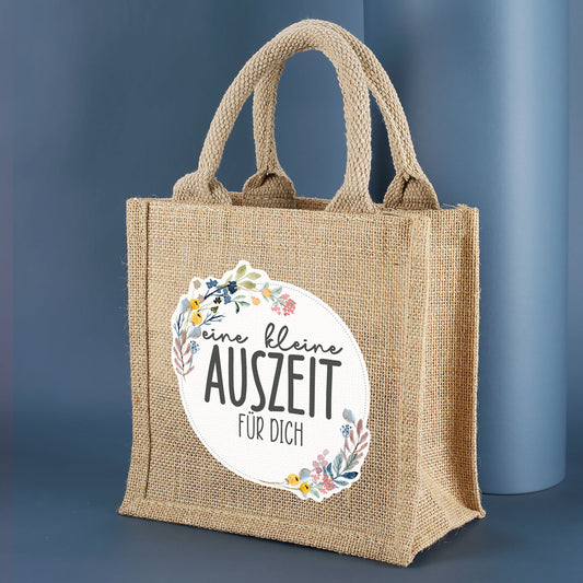 Personalisierte Geschenktasche aus Jute "eine kleine Auszeit" seitlich fotografiert vor dunkelblauem Hintergrund