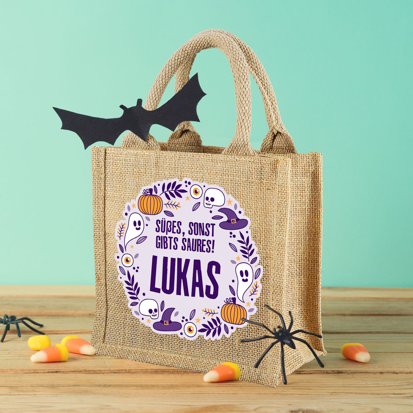 Halloween-Jutebeutel mit personalisiertem Namen und Süßigkeiten-Deko auf hellem Hintergrund.