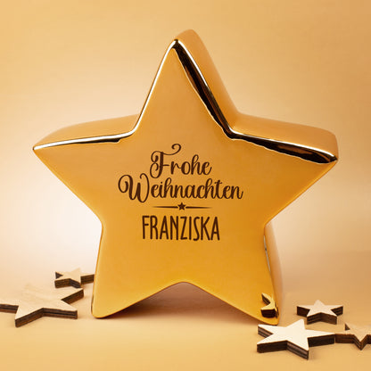 Leonardo Keramikstern in Gold mit Weihnachtsmotiv und Namen, fotografiert im warmen Licht