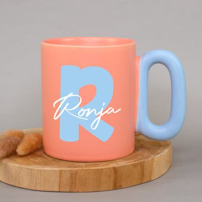 Korallfarbene Tasse mit Initiale R und Name Ronja auf Holzunterlage