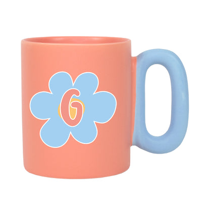 Freigestellte korallfarbene Tasse mit Blumenmotiv und Initiale