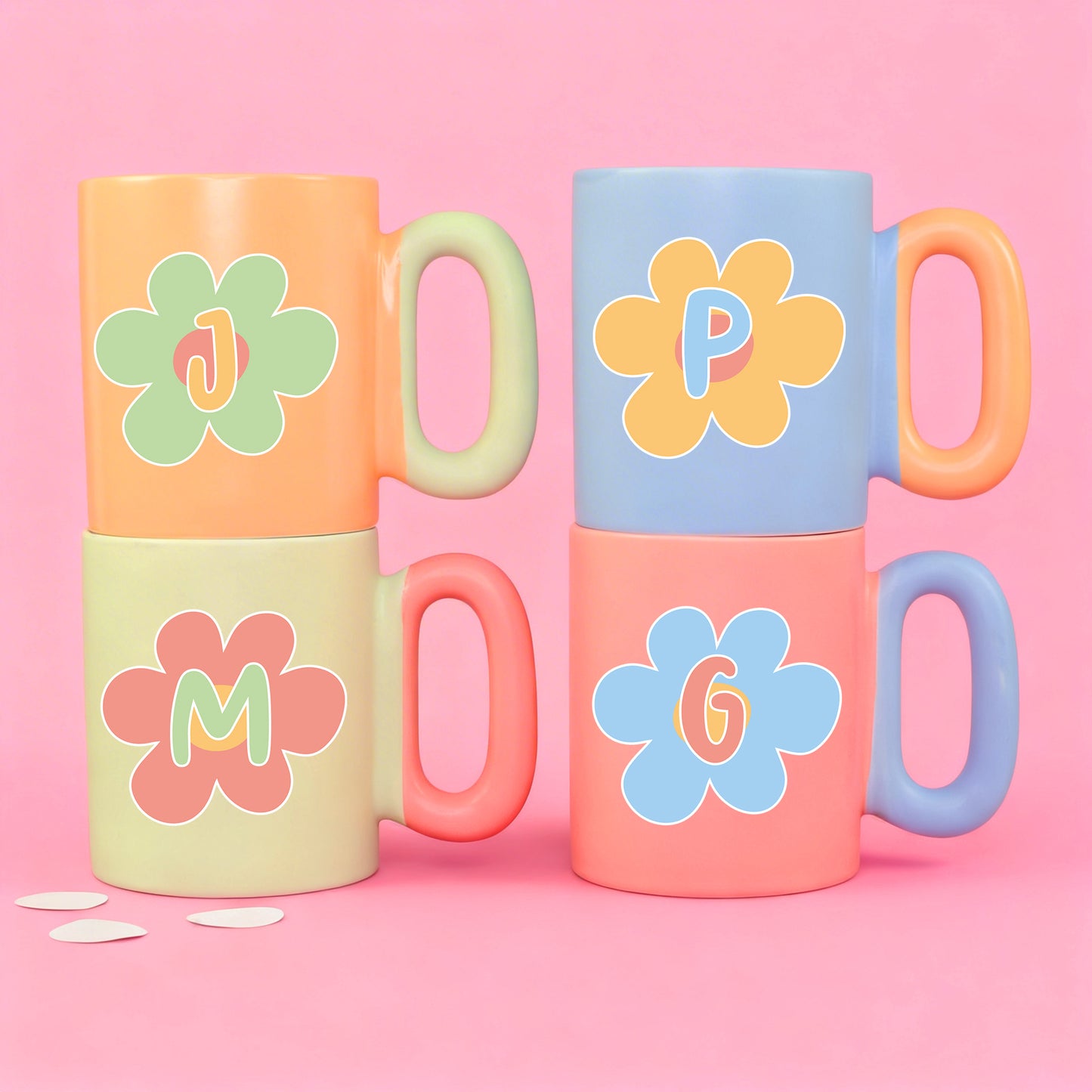 Vier bunte Tassen mit Blumenmotiv und Initialen in Pastellfarben im Set dargestellt