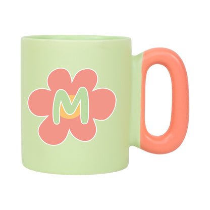Freigestellte grüne Tasse mit Blumenmotiv und Initiale