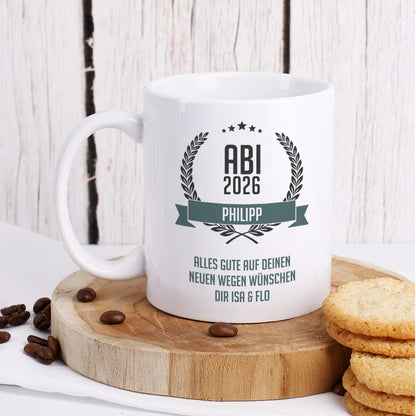 Glückwunsch-Tasse zum Abitur mit Name "Philipp" und Wunschtext dekoriert auf Baumscheibe mit Keksen und Kaffeebohnen