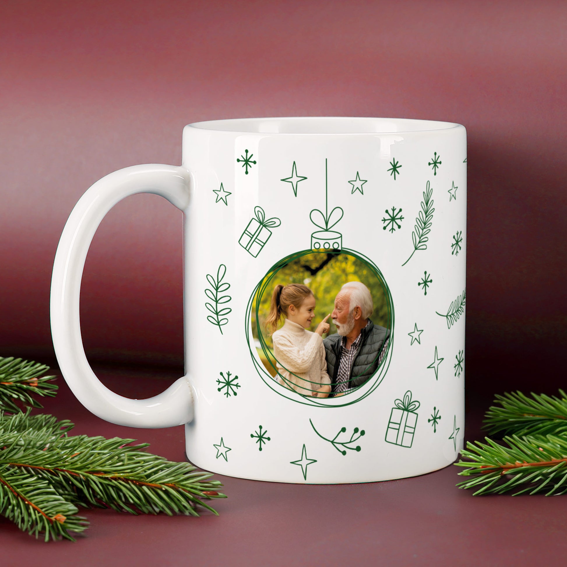 Weiße Fototasse mit grünem Weihnachtskugel-Design, integriertem Familienfoto und festlichen Illustrationen aus Sternen, Tannenzweigen und Geschenken.
