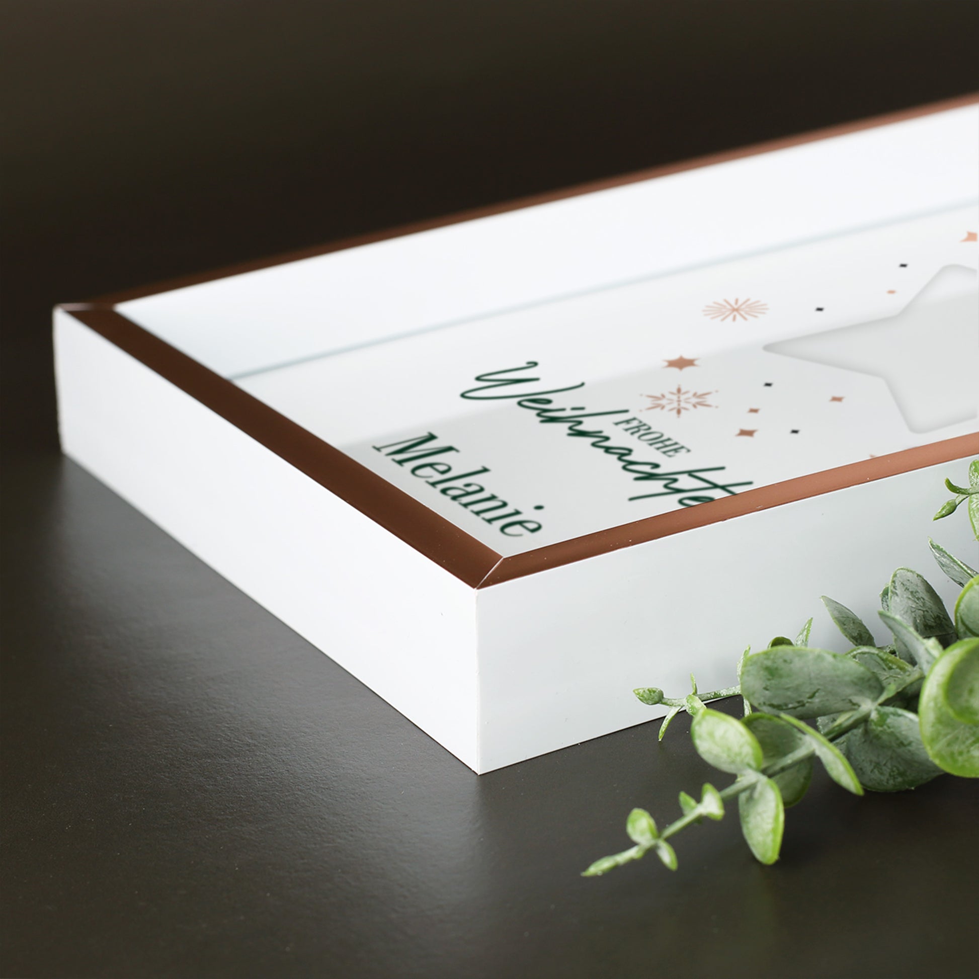 Seitliche Detailaufnahme des roségoldenen Bilderrahmens mit weißem Rand und weihnachtlichem Sternmotiv