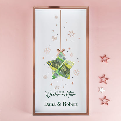 Geldgeschenk Bilderrahmen zu Weihnachten mit Namen Dana und Robert, Stern-Aussparung und Euro-Scheinen vor rosa Wand