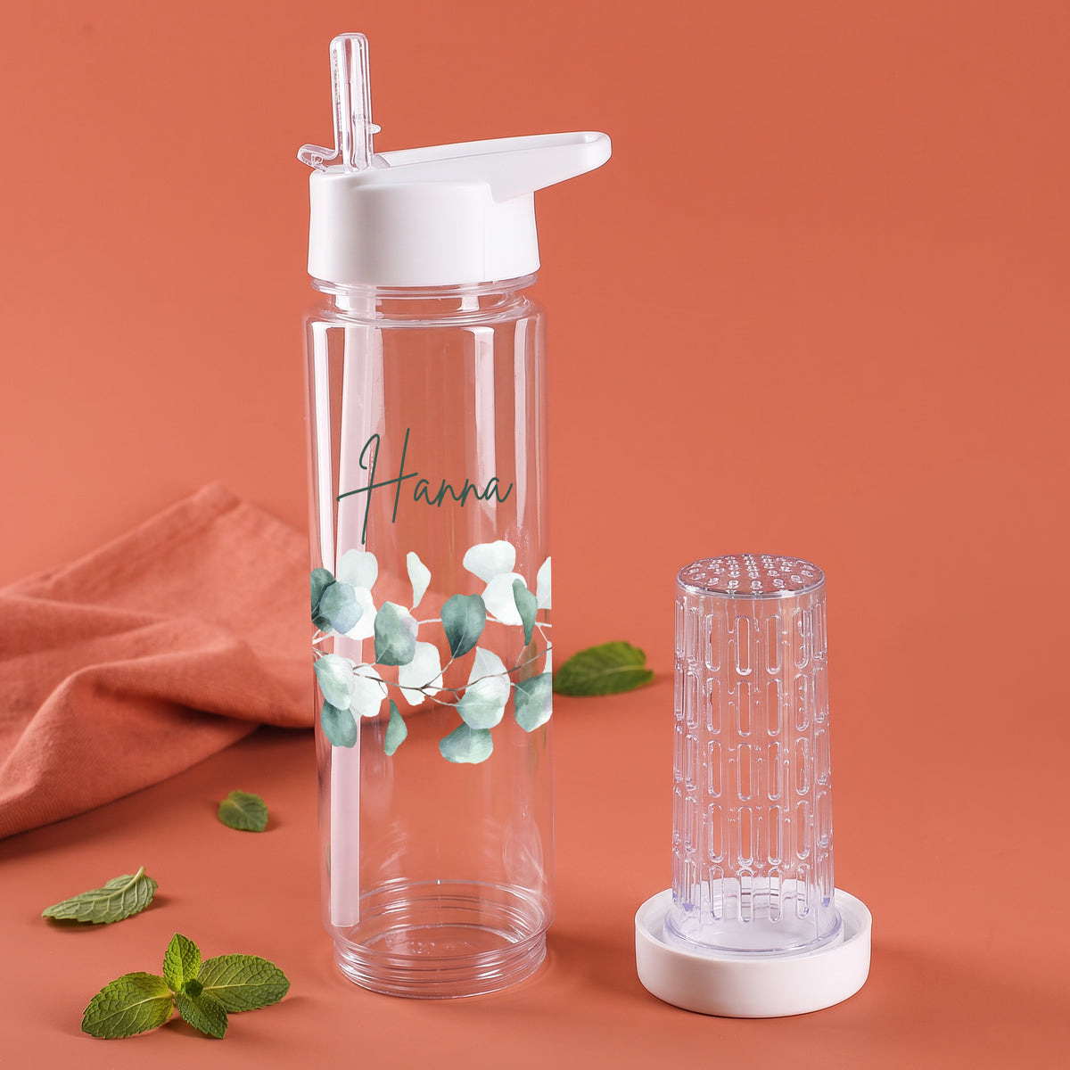 Personalisierte Trinkflasche mit Name Hanna und Eukalyptus-Motiv neben herausnehmbarem transparentem Fruchteinsatz