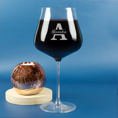 Leonardo Burgunderglas mit Gravur von Initiale A und Name Alexandra, auf blauem Hintergrund mit Teelicht im Glasgefäß.