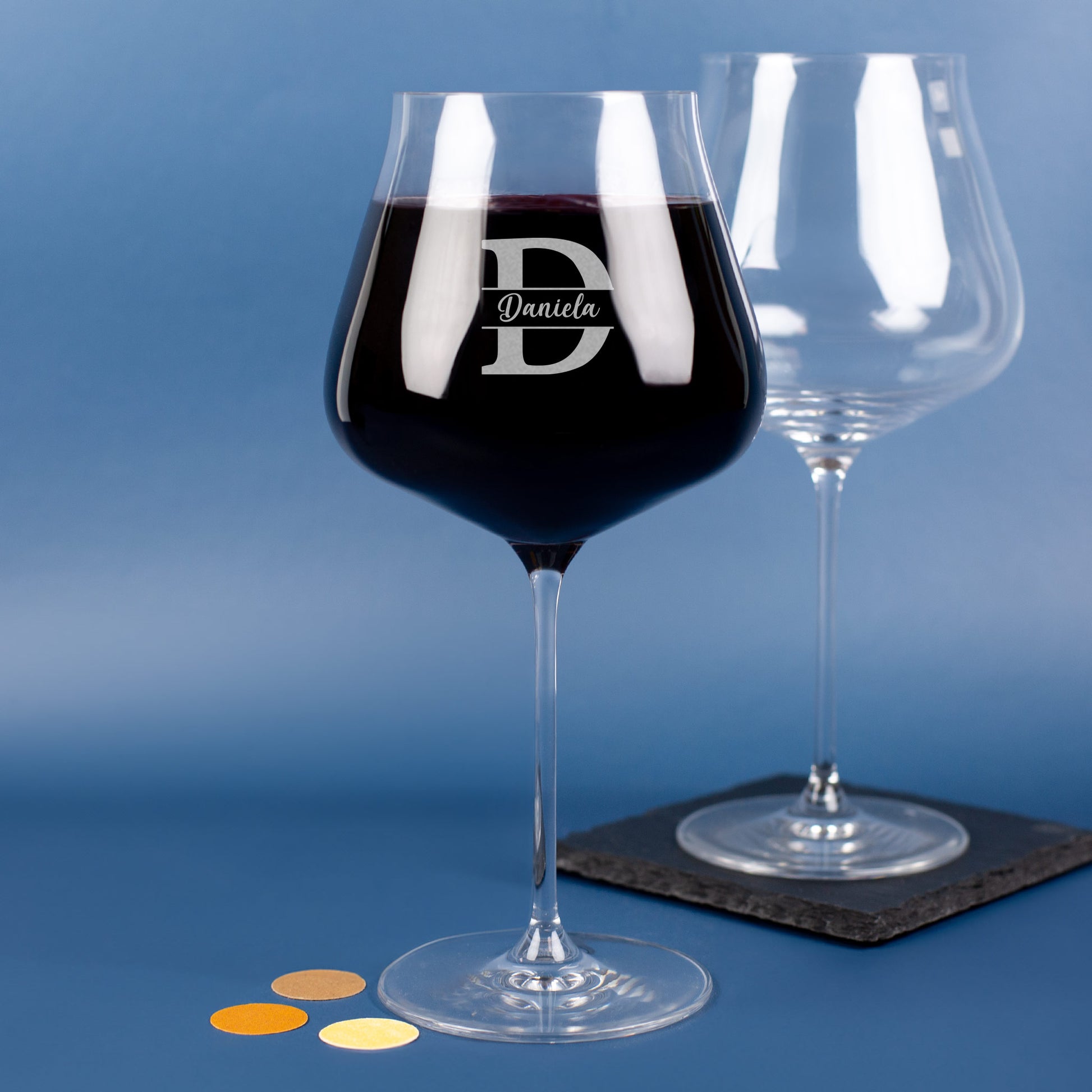 Zwei Burgundergläser von Leonardo, eines graviert mit Initiale D und Name Daniela, eines leer im Hintergrund.