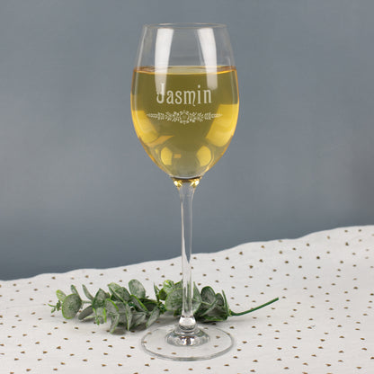 Leonardo Weißweinglas mit Gravur Jasmin und floralem Blätter-Ornament, gefüllt mit Weißwein, auf grauem Hintergrund