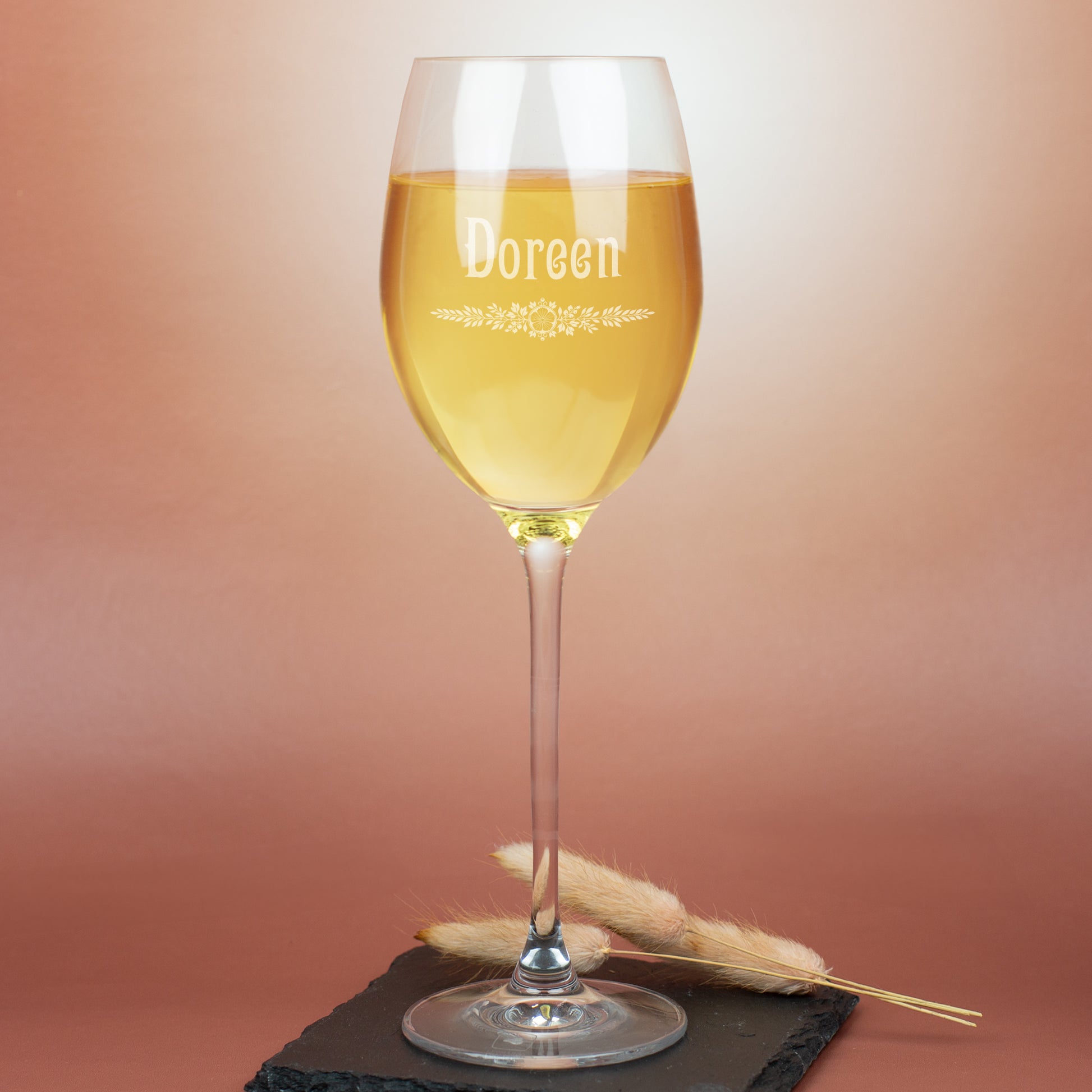 Personalisiertes Leonardo Weißweinglas mit Gravur Doreen und floralem Ornament, auf warmem Hintergrund mit Deko