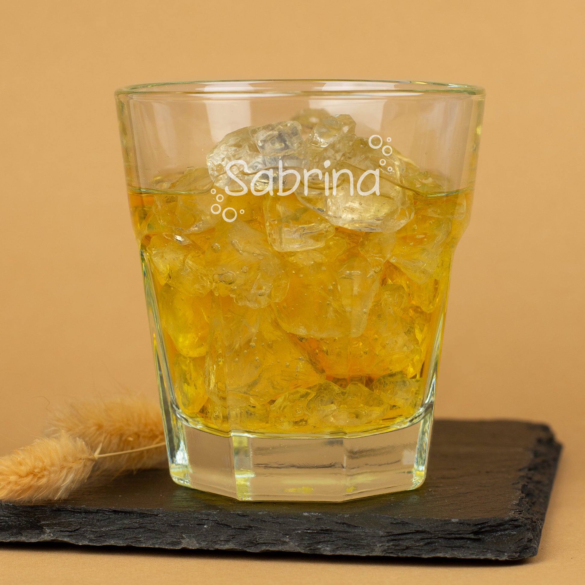 Leonardo-Kindertrinkglas mit graviertem Namen und Blasenmuster, gefüllt mit Saft, auf Schieferplatte – personalisiertes Glas für Kinder.