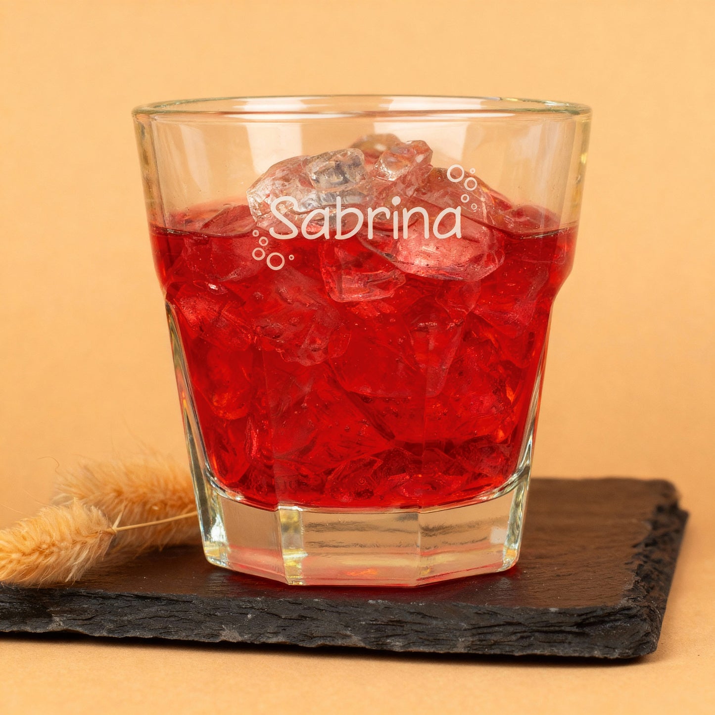 Leonardo-Trinkglas mit graviertem Namen und Blasen-Motiv, gefüllt mit rotem Saft, auf dunkler Schieferplatte – liebevolles Kinder- und Familienglas.