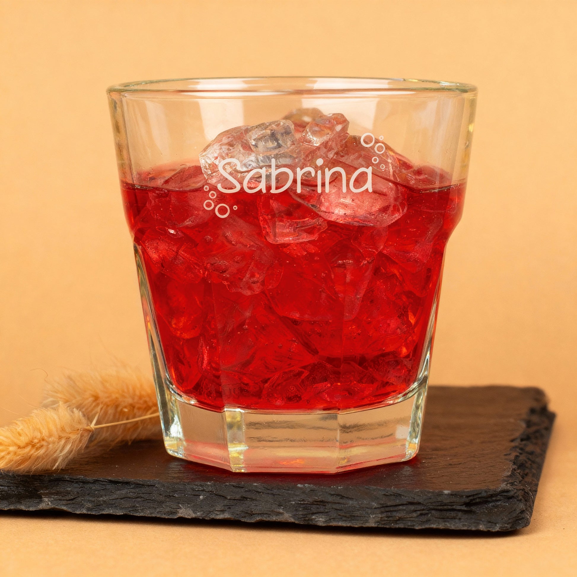 Leonardo-Trinkglas mit graviertem Namen und Blasen-Motiv, gefüllt mit rotem Saft, auf dunkler Schieferplatte – liebevolles Kinder- und Familienglas.