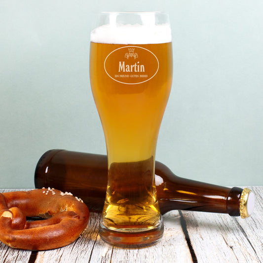 Gefülltes Weizenglas mit Gravur Martin, daneben Bierflasche und Brezel
