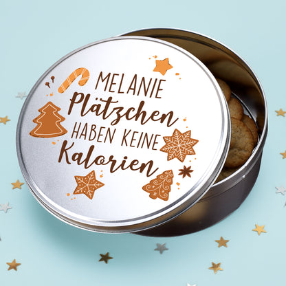 Runde Metalldose mit Spruch „Plätzchen haben keine Kalorien“ und Name Melanie, gefüllt mit Weihnachtsplätzchen auf einem hellblauen Hintergrund.