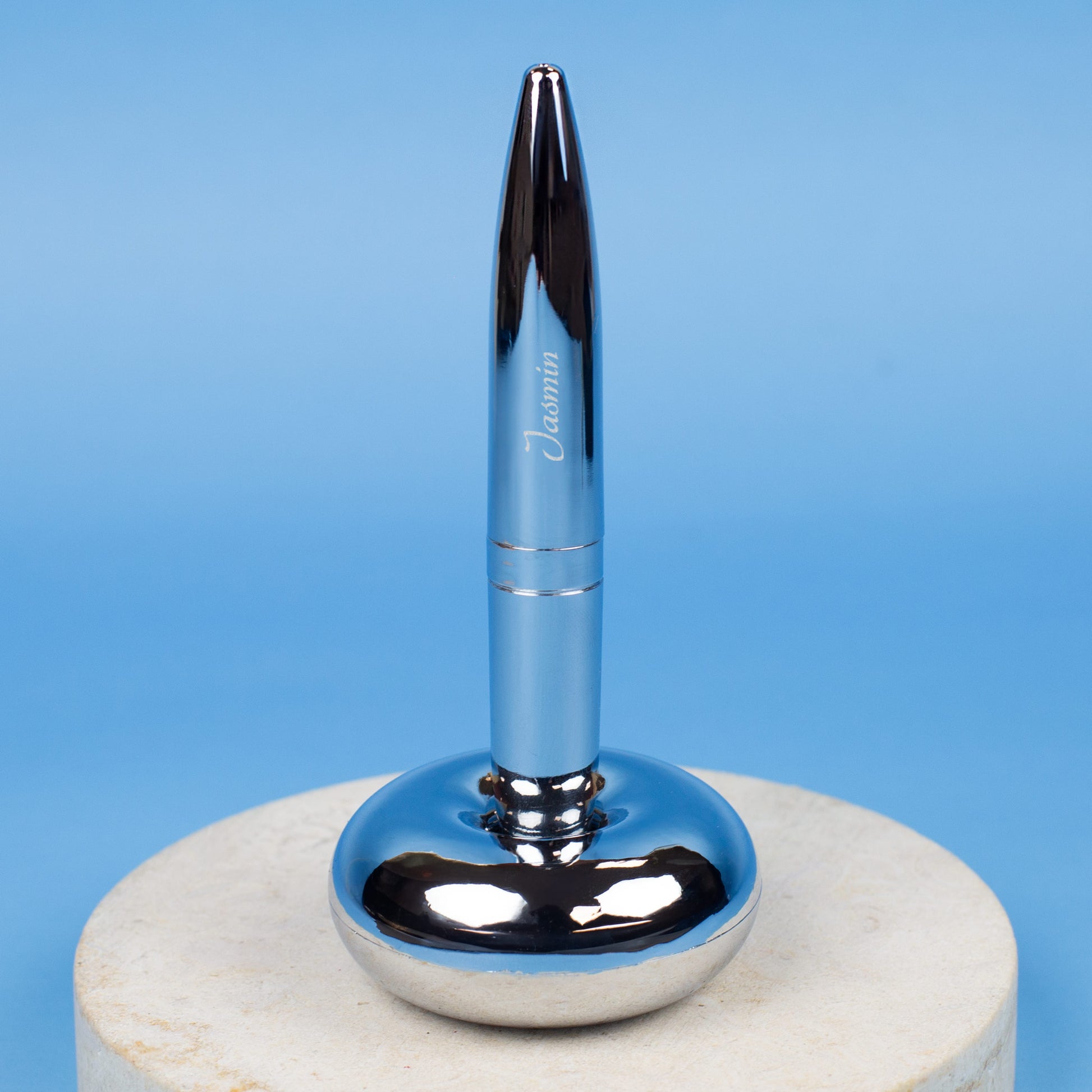 Magischer Kugelschreiber mit Namensgravur stehend in Ständer auf blauem Hintergrund