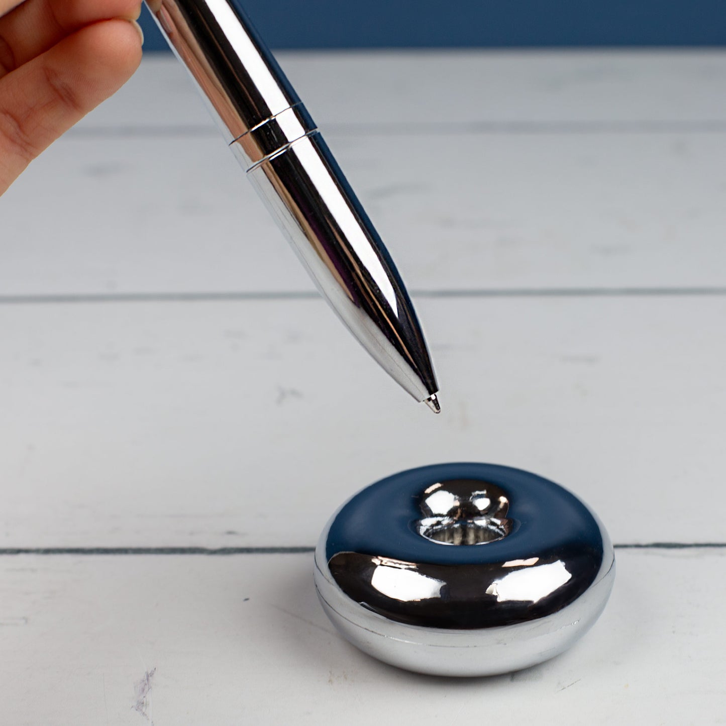 Magischer Kugelschreiber mit Namensgravur gehalten von einer Hand über Ständer