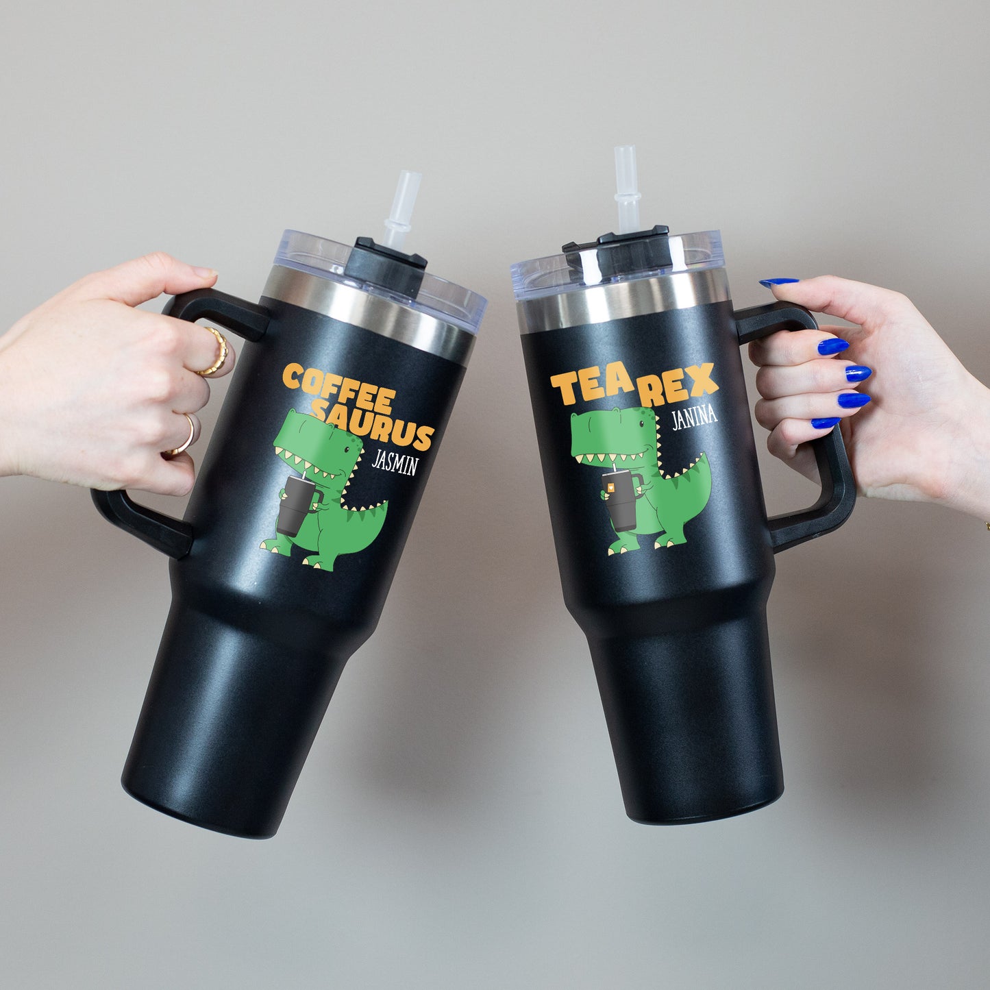 Beide Varianten des Thermobecher mit grünem Dino und orangem Schriftzug in Händen gehalten