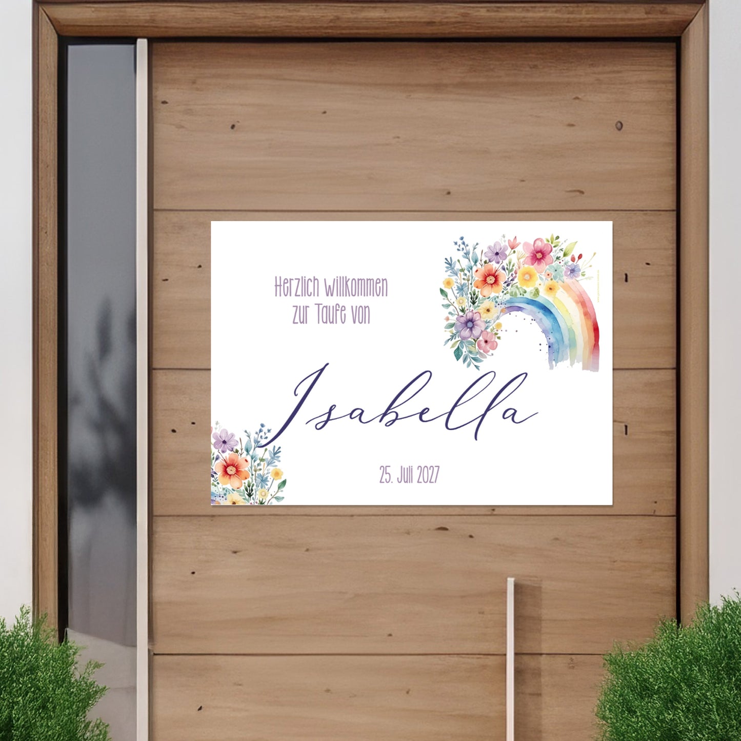 Personalisierbares Banner mit Regenbogen- und Blumenmotiv an einer Holztür befestigt. Text: „Herzlich willkommen zur Taufe von Isabella – 25. Juli 2027“. Außenansicht zur Veranschaulichung des Einsatzes im Außenbereich.