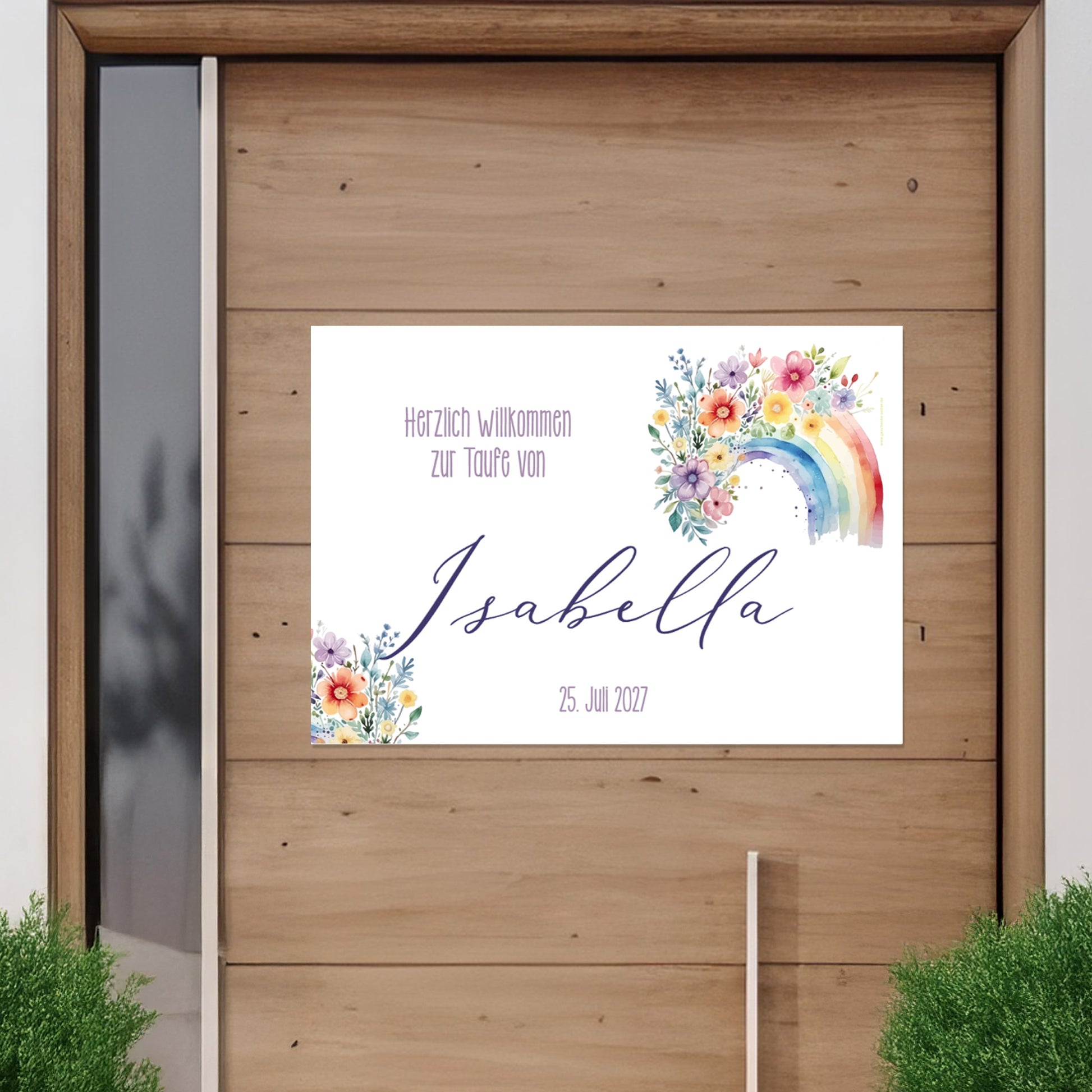 Personalisierbares Banner mit Regenbogen- und Blumenmotiv an einer Holztür befestigt. Text: „Herzlich willkommen zur Taufe von Isabella – 25. Juli 2027“. Außenansicht zur Veranschaulichung des Einsatzes im Außenbereich.