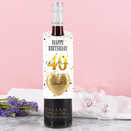Großer Flaschenanhänger zum Geburtstag mit Konfetti-Motiv, personalisiertem Namen und Alter sowie goldenem Lindt-Herz – auf einer Flasche platziert.