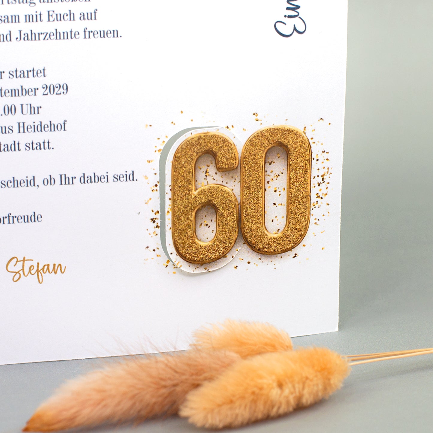 Nahaufnahme der Einladungskarte mit goldfarbener 60 zum runden Geburtstag