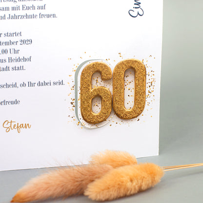 Nahaufnahme der Einladungskarte mit goldfarbener 60 zum runden Geburtstag