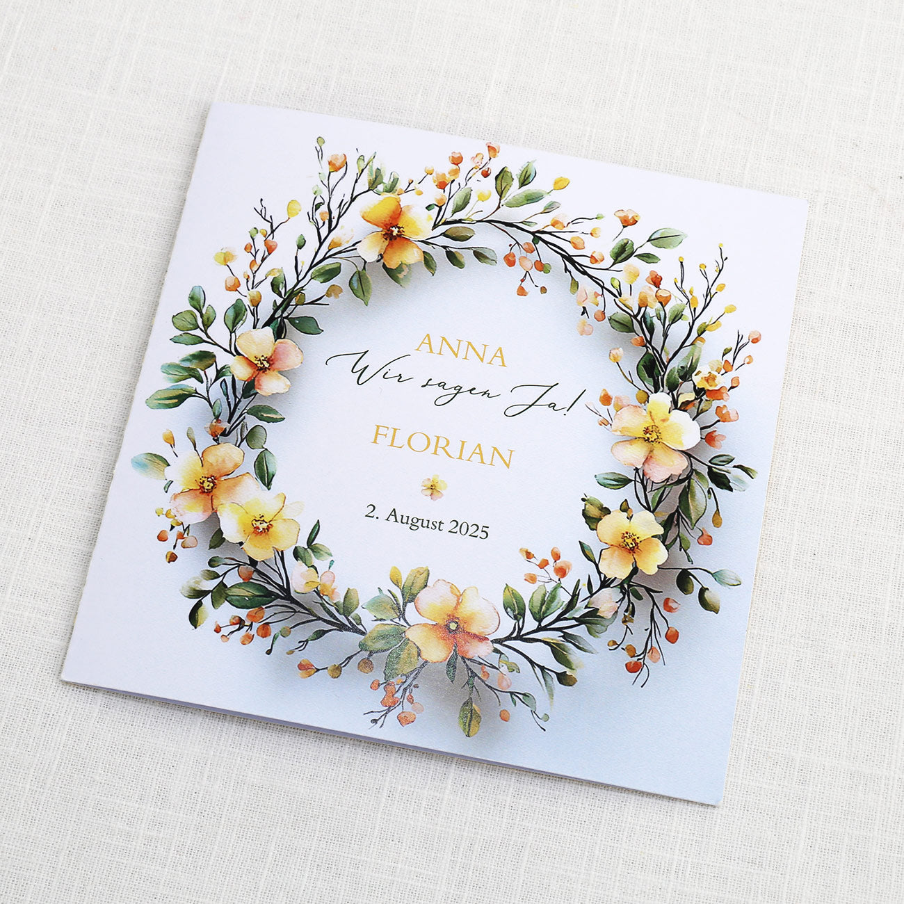 Einladungskarte zur Hochzeit mit Blütenkranz und rundem Anhänger