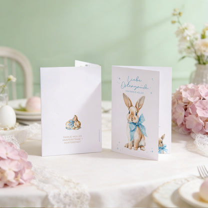 Aufgestellte Oster Klappkarte mit niedlichem Hasenmotiv und personalisiertem Text auf einem festlich gedeckten Tisch