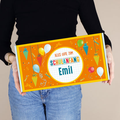 Mittlere personalisierte Aufbewahrungsbox aus Pappe mit Wunschname und buntem Schulanfang-Motiv, von einer Person gehalten