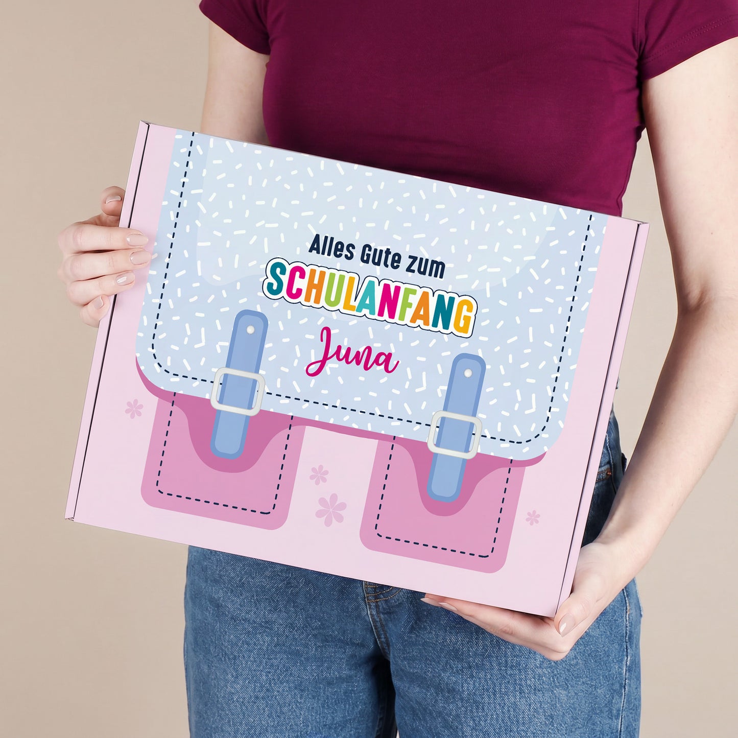 Große rosa Geschenkbox zum Schulanfang mit Name, von einer Person gehalten