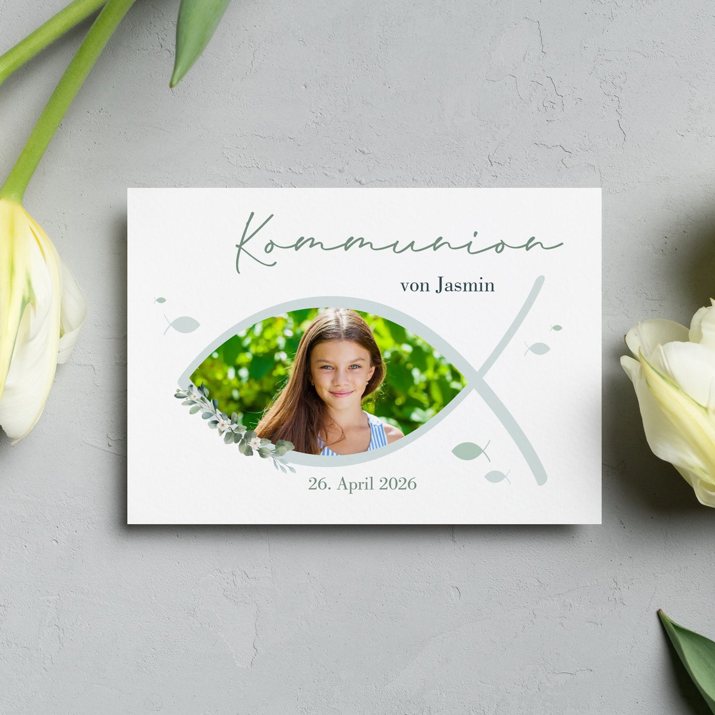 Personalisierte Einladungskarte zur Kommunion mit christlichem Fischsymbol (Ichthys). Vorderseite mit individuellem Foto, sanften Grüntönen und stilvollen Blätterelementen.
