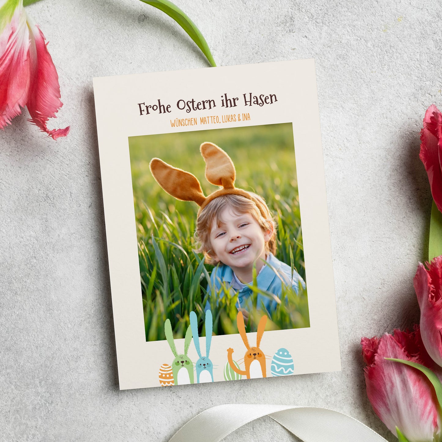 Osterkarte mit Foto eines Kindes und Hasenmotiv im Gras mit Frühlingsdeko