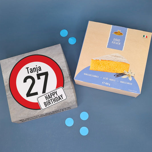 Kuchenbox mit Verkehrszeichen „27“ und Name Tanja, daneben Vanillekuchenverpackung und blaue Deko-Konfetti