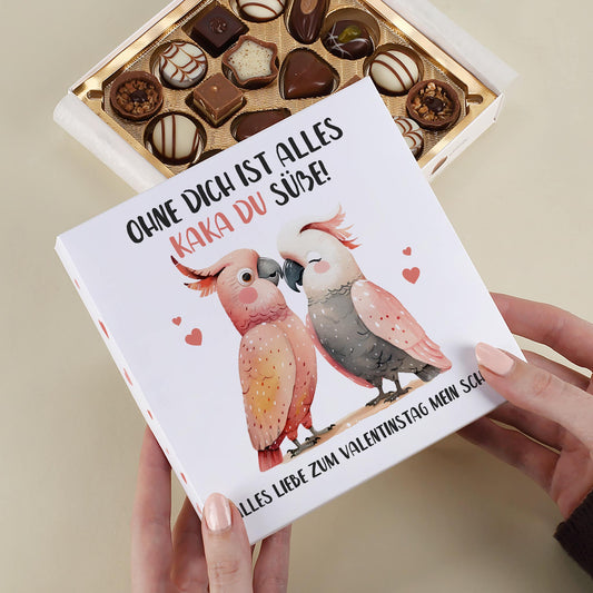 Lindt Pralinenbox mit Kakadu-Pärchen und personalisiertem Wunschtext als Valentinstagsgeschenk in der Hand gehalten