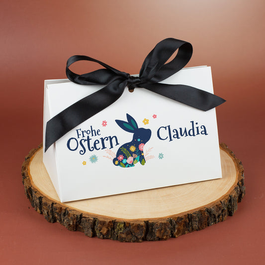 Große weiße Geschenkverpackung zu Ostern mit Hasenmotiv und Name Claudia auf Holzunterlage