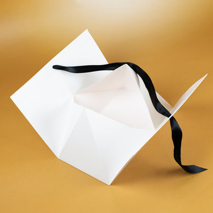 Innenansicht der geöffneten Geschenktasche mit Faltkonstruktion und losem Satinband auf goldenem Hintergrund.