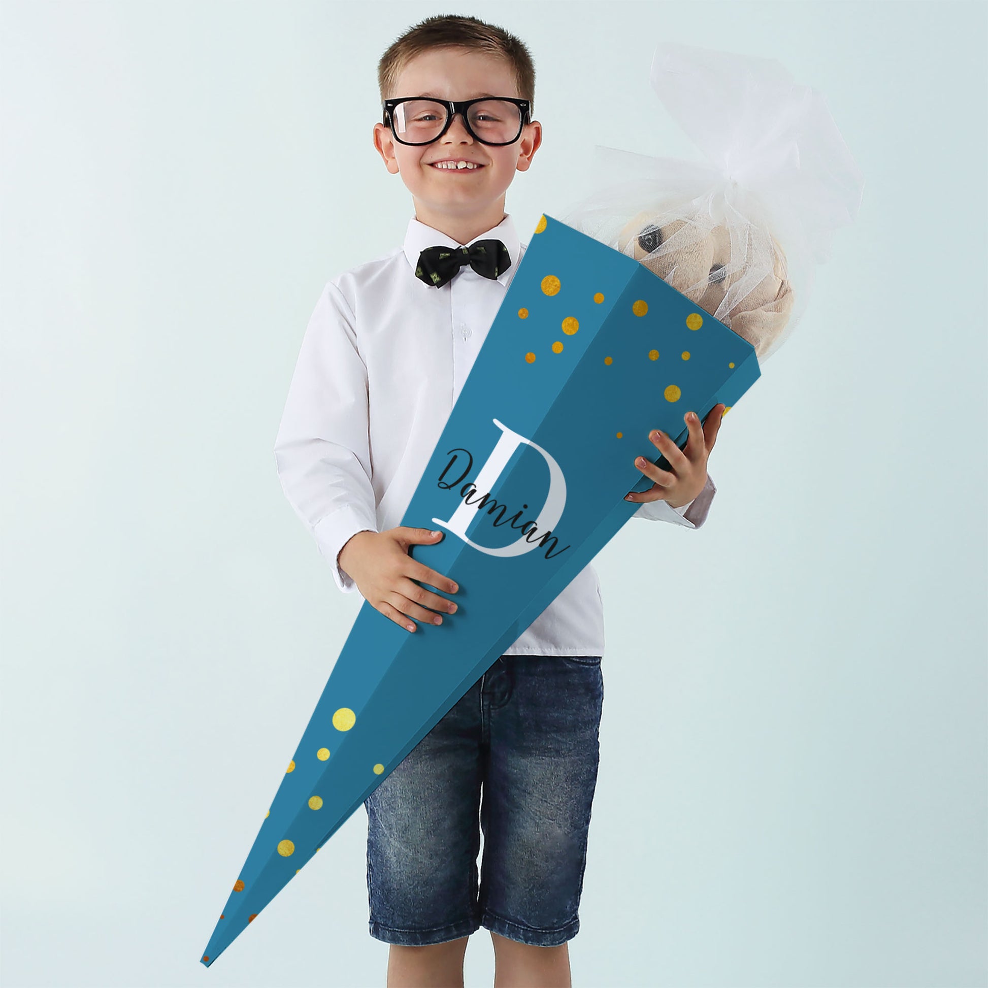 Junge mit großer Schultüte in Dunkelblau, bedruckt mit Initiale und Namen