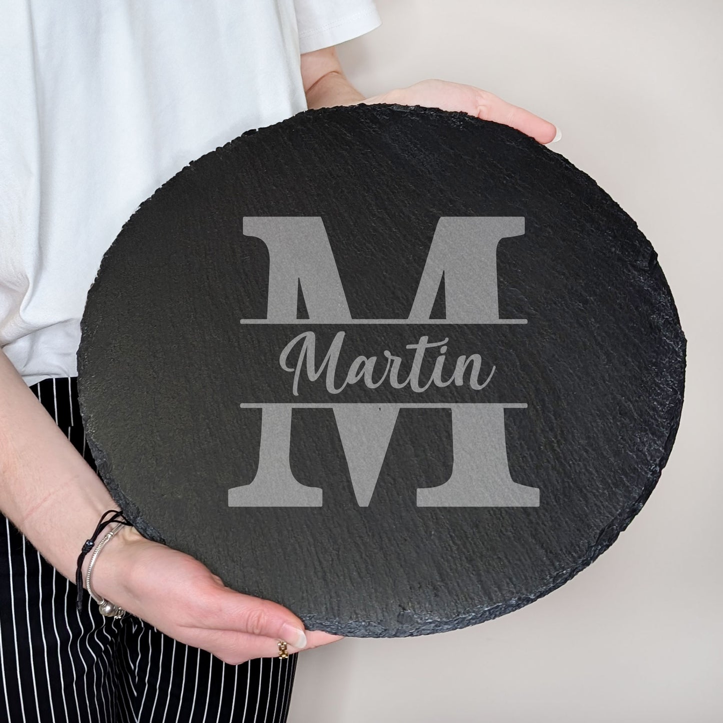 Runde Schieferplatte mit Gravur von Name und Initiale "Martin", von zwei Händen gehalten