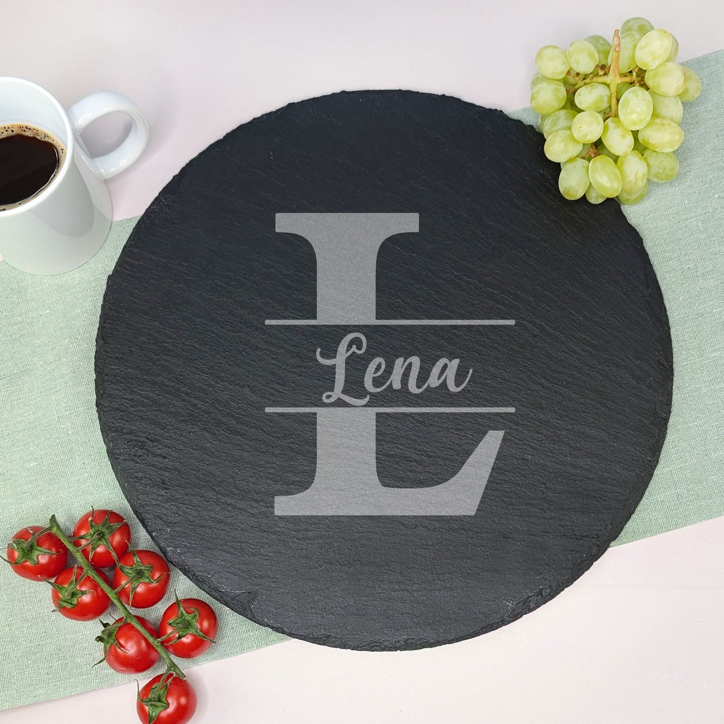 Personalisierte Schieferplatte mit Gravur des Namens und großer Initiale, dekoriert mit Weintrauben, Tomaten und Kaffee.