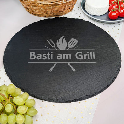 Runde Schieferplatte mit Wunschtext Gravur und Motiv, dekoriert mit Camembert, Tomaten, Korb und Weintrauben.