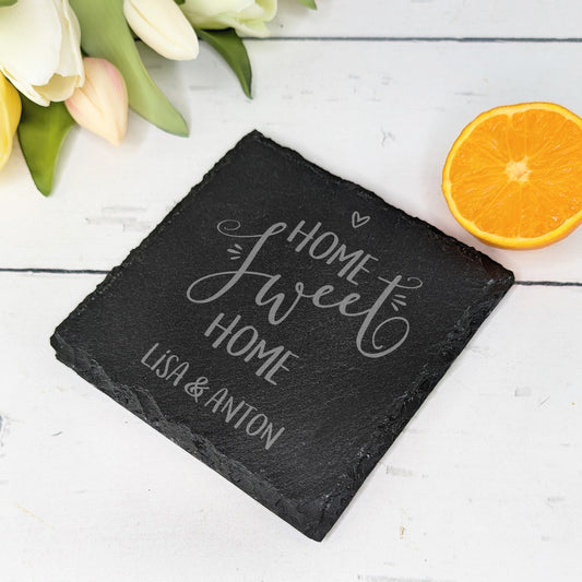 Schiefer-Untersetzer mit „Home sweet Home“-Gravur und Blumendeko auf hellem Tisch