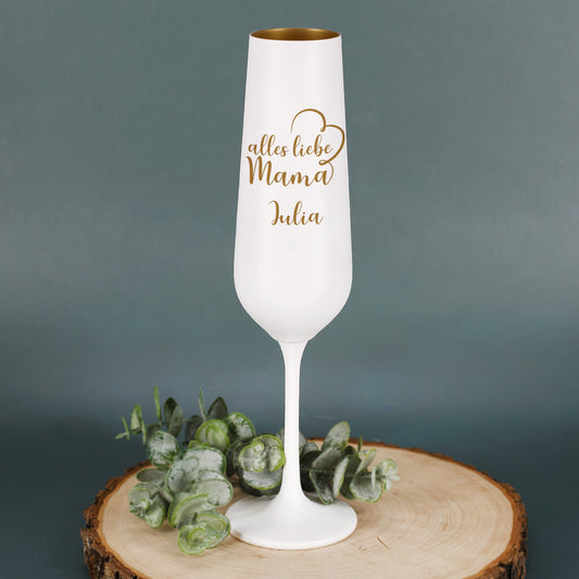 Weiß-goldenes Sektglas mit Gravur „alles liebe Mama“ und Name Julia, eingerahmt von einem Herz, auf Holzplatte mit Blumen