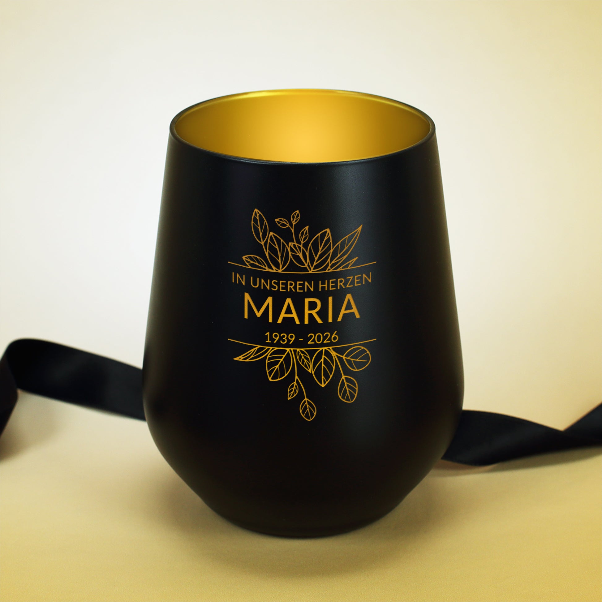 Schwarzes Windlicht symbolisch mit einem schwarzen Stoffband dekoriert