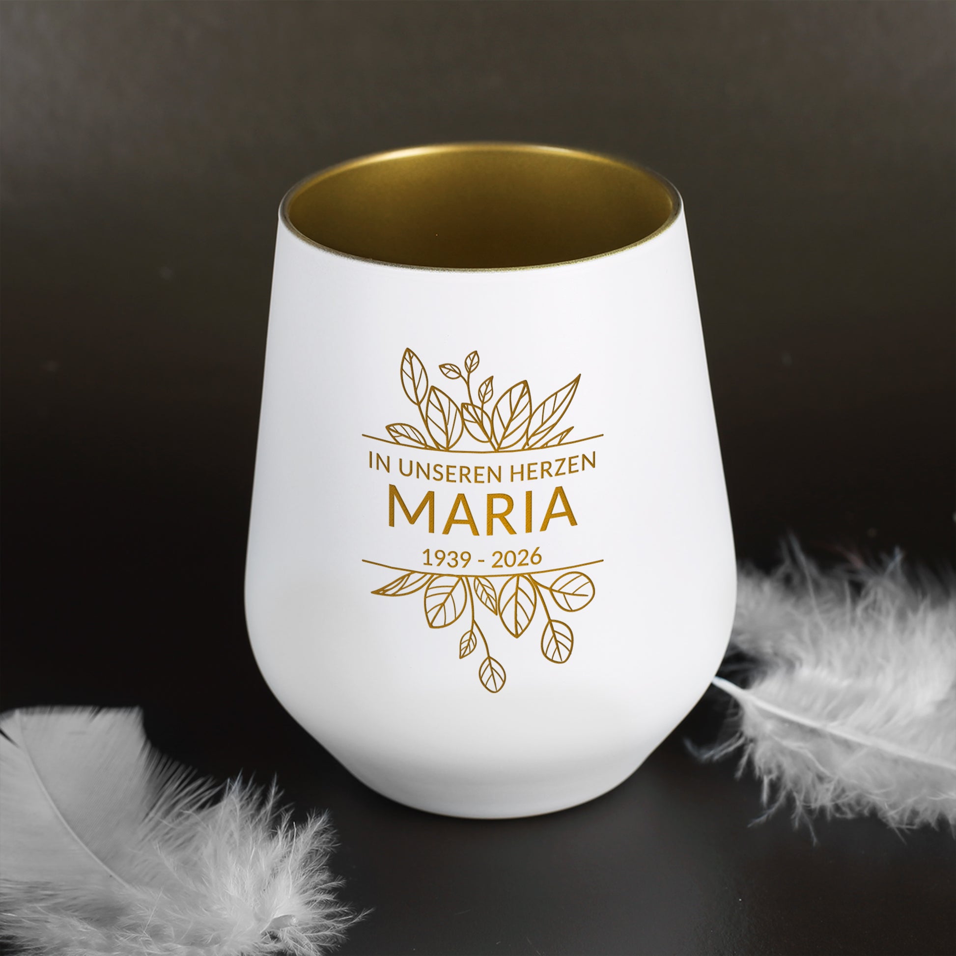 Weißes Windlicht symbolisch neben Federn dekoriert