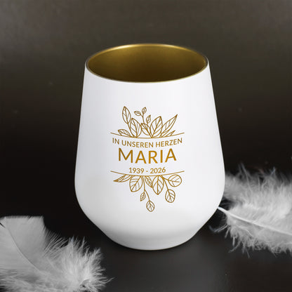 Weißes Windlicht symbolisch neben Federn dekoriert